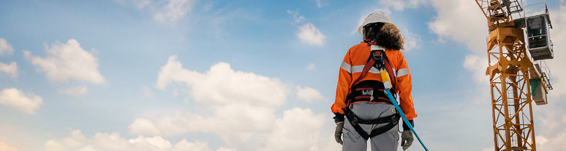 Contstruction woman wearing safety harness looking up at the sky